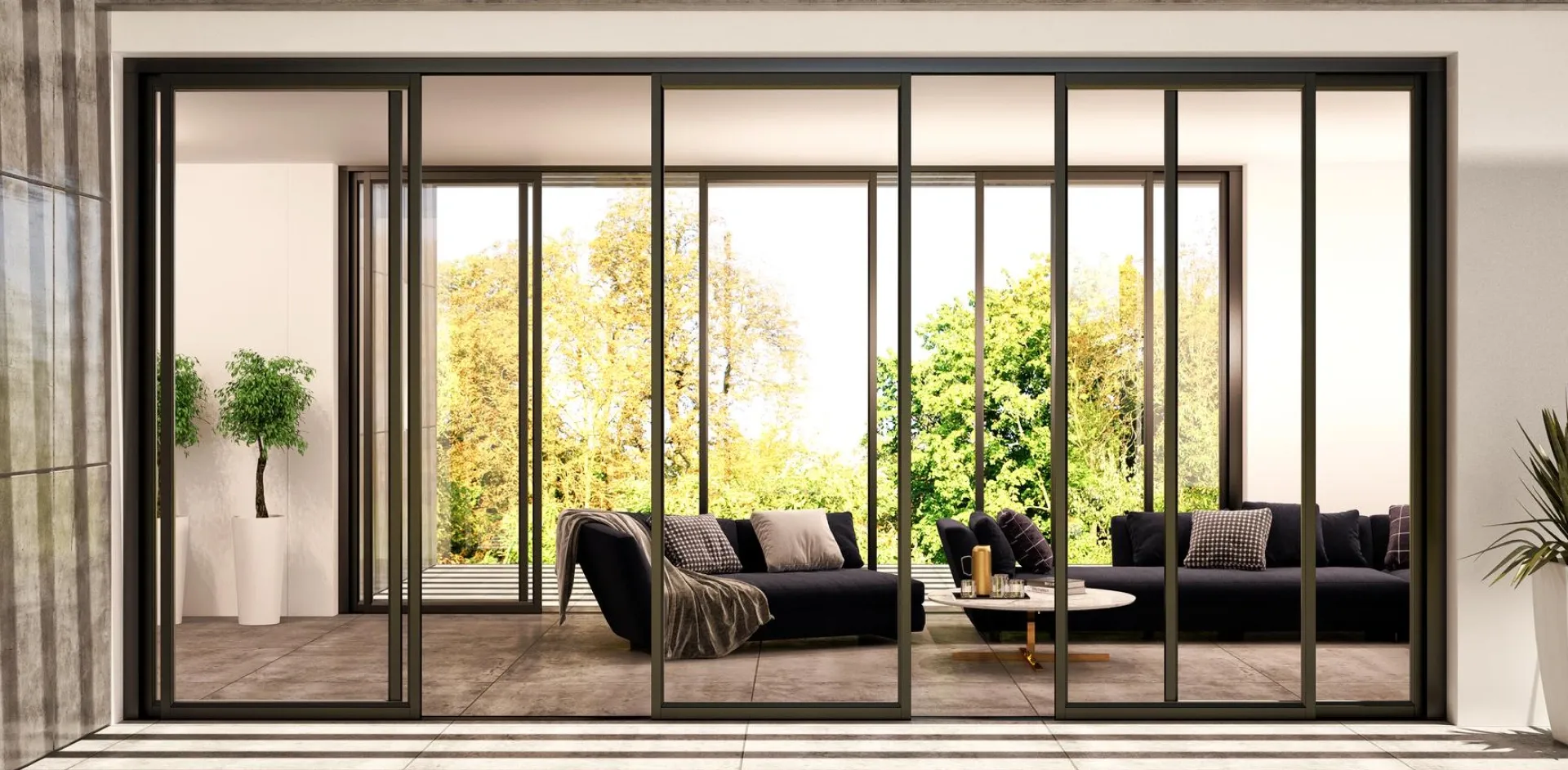 Black aluminium stacker doors with six glass panels opening a living room onto a paved terrace
