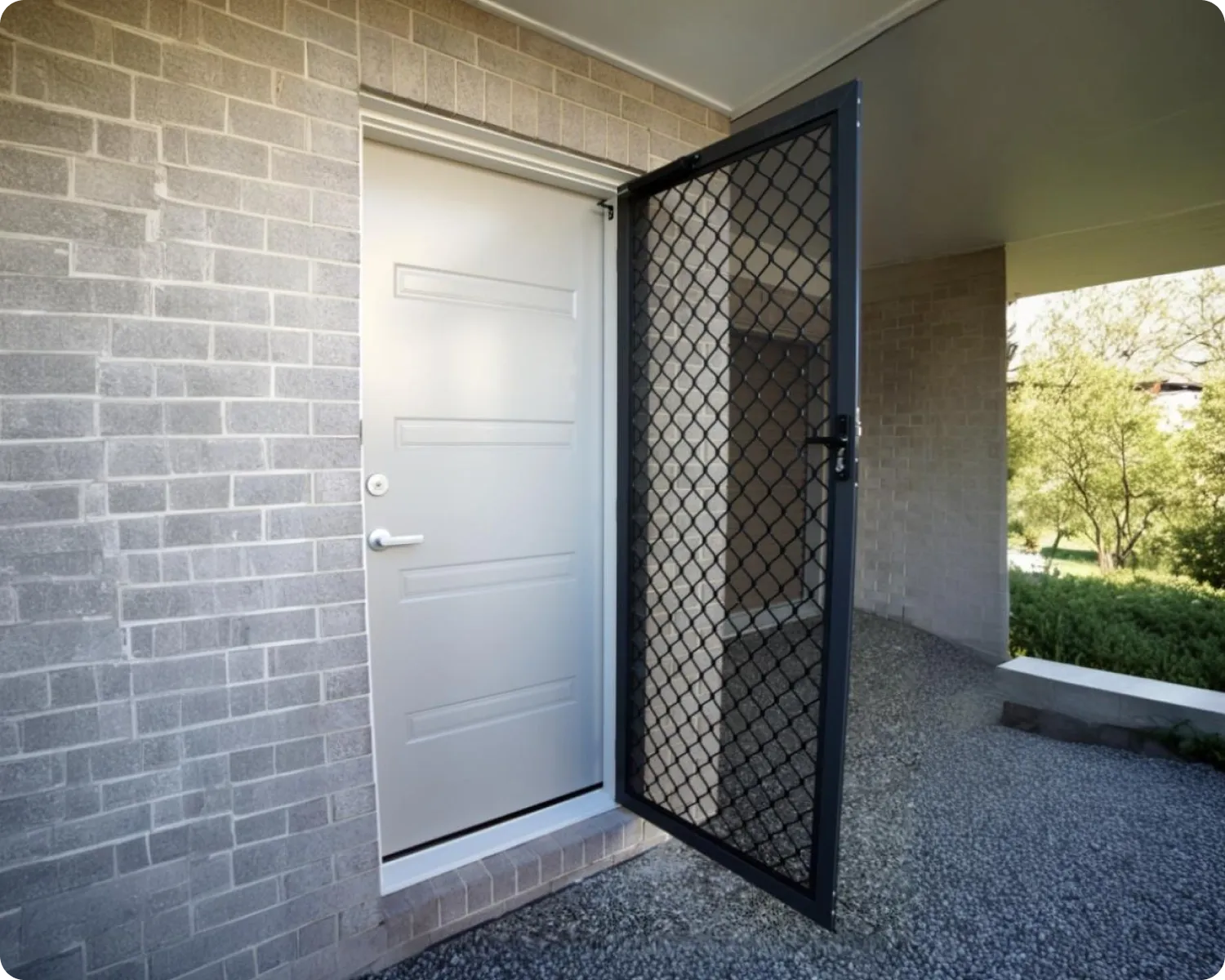Grey diamond grille safety screen door standing open beside a white front door on a brick home