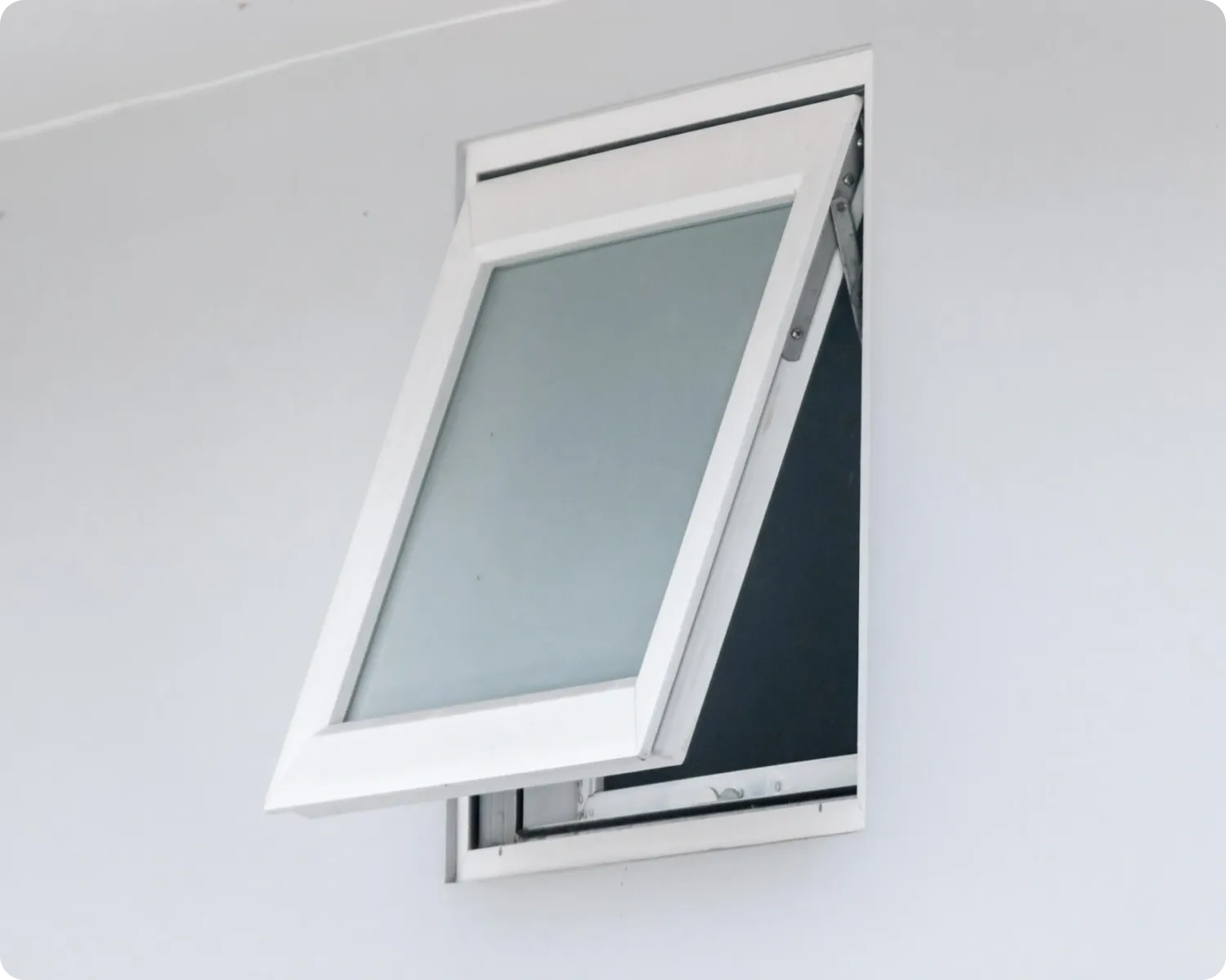 White aluminium awning window with frosted glass winched open on a plain white wall