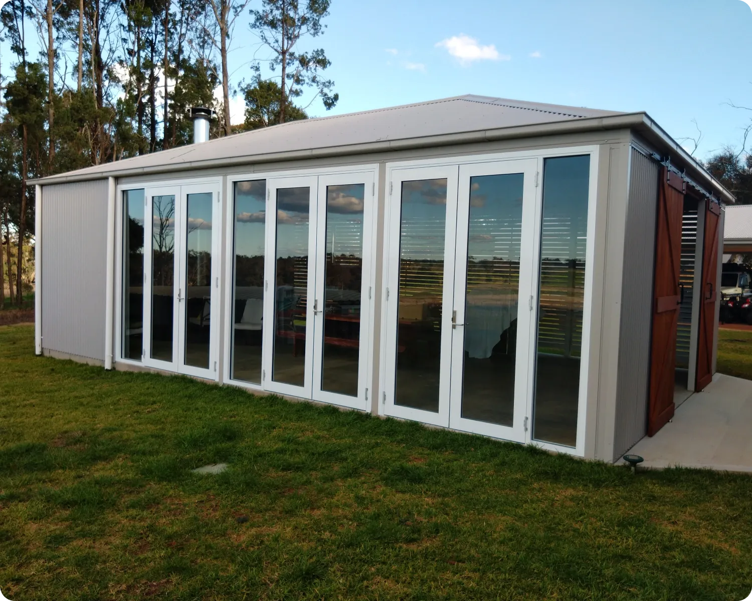 White aluminium bi-fold doors across the front of a garden studio, panels closed