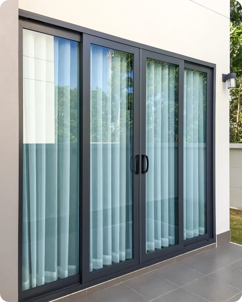 Charcoal powder-coated aluminium sliding door with black handles, seen from a tiled patio