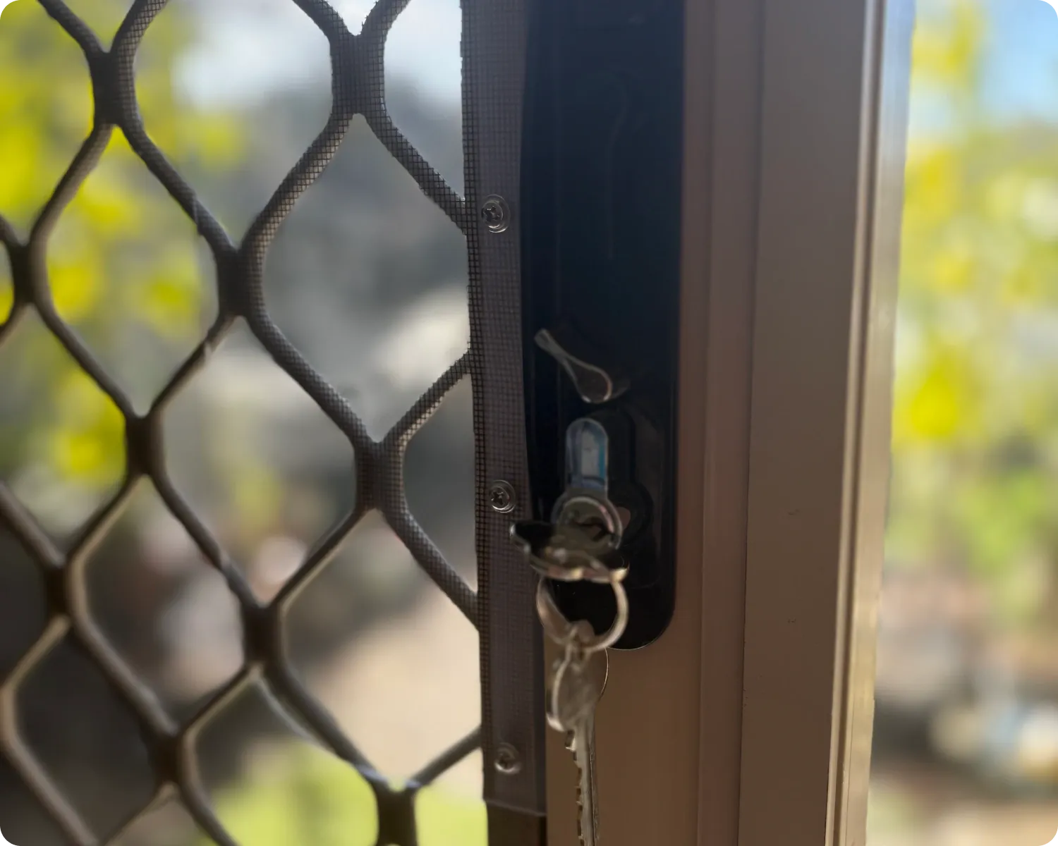 Close-up of the keyed lock and keys on a diamond grille safety screen door
