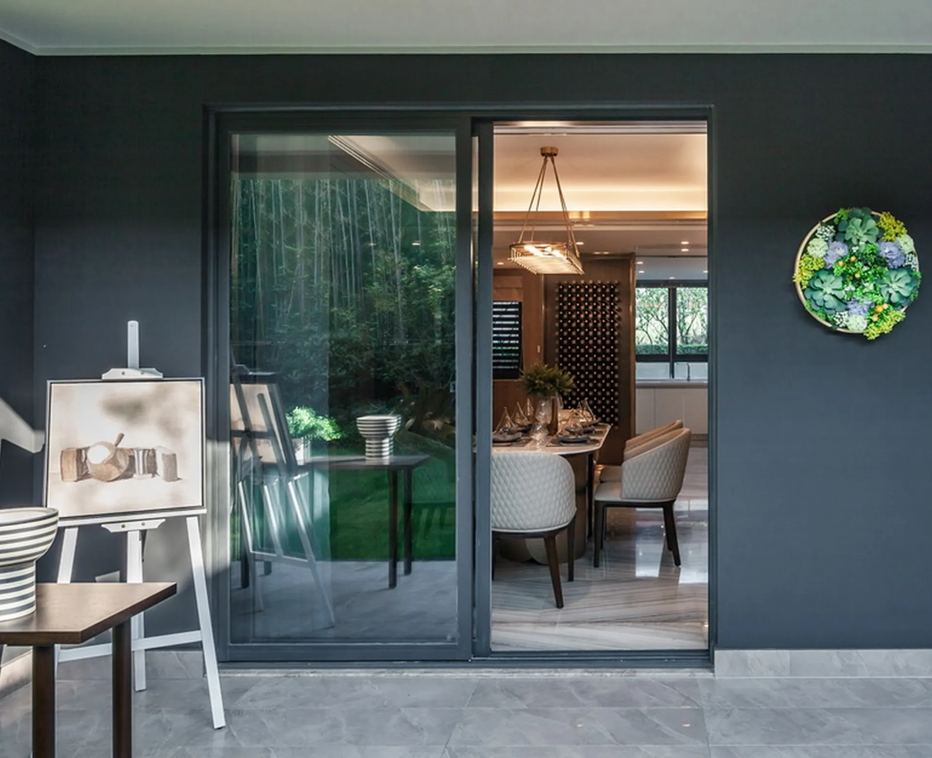 Dark grey aluminium sliding door standing open between a covered patio and a dining room